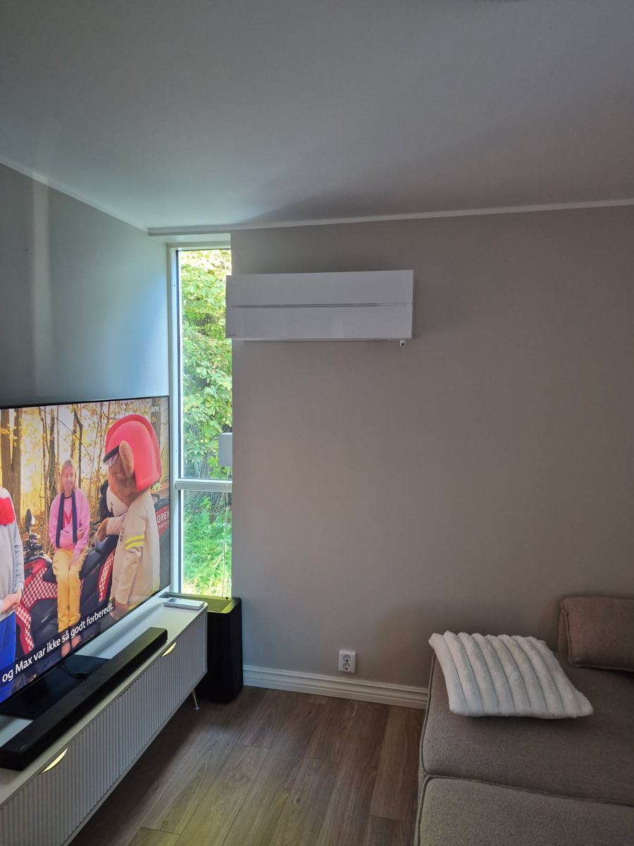 Innedel til varmepumpe montert over TV-en i en stue