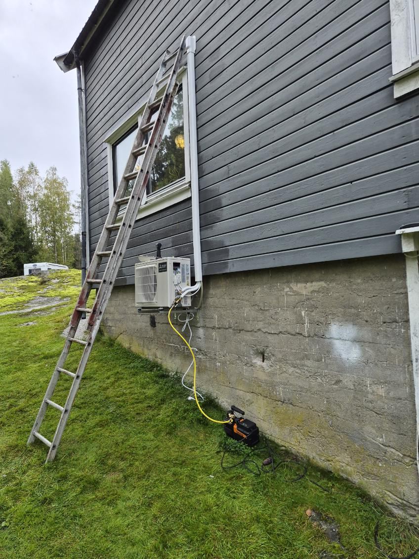 Stige mot husvegg der utedelen til en varmepumpe monteres på veggkonsoll
