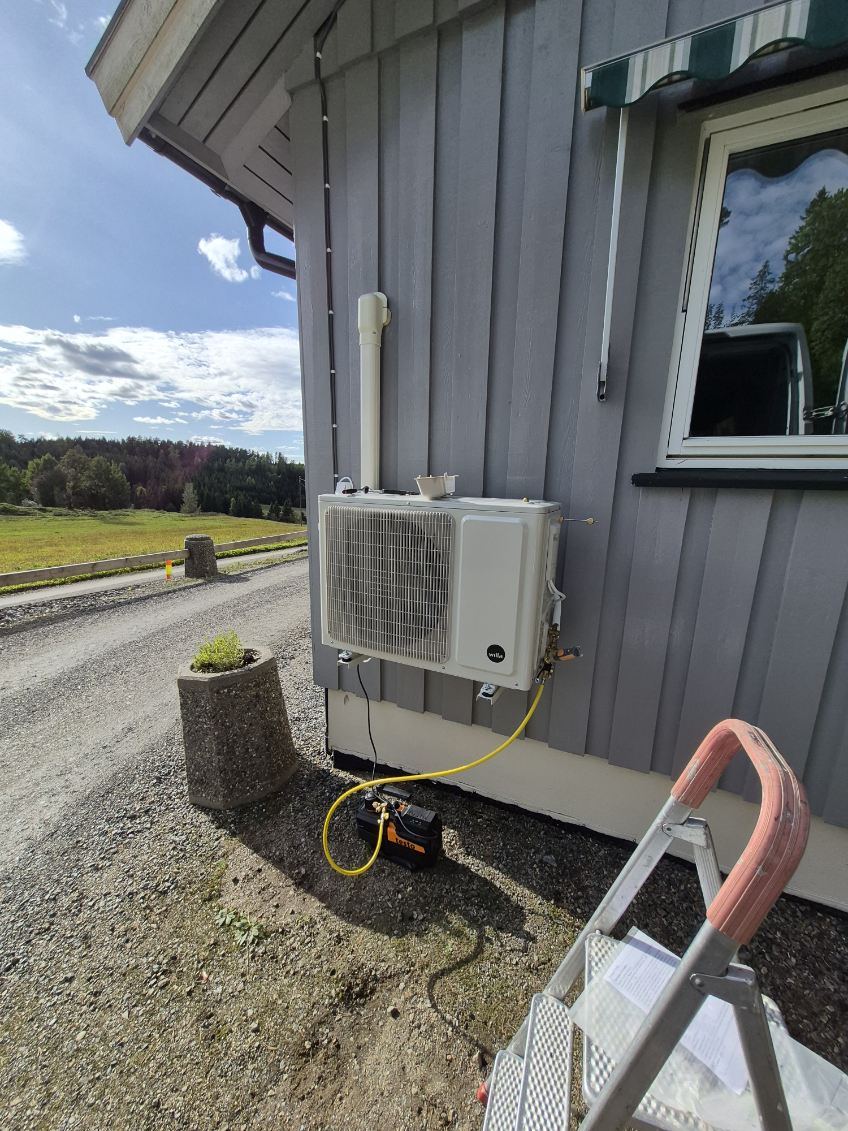 Utedel til varmepumpe på veggkonsoll ved en grusvei